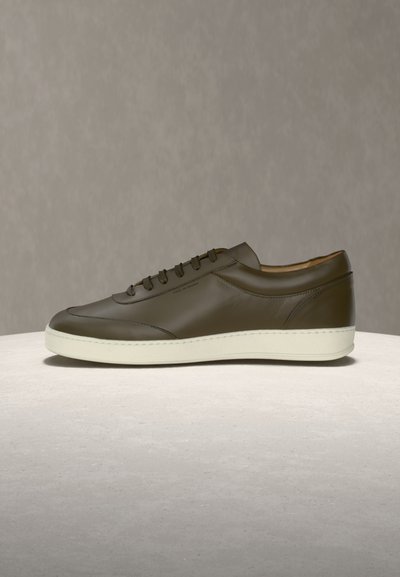 Niskie trampki z ciemnooliwkowej skóry, biała gumowa podeszwa, sznurowane, z subtelnymi detalami szwów na neutralnym tle.