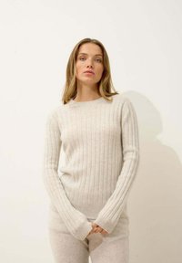 Jasnoszary sweter w prążki wykonany z miękkiego materiału, z długimi rękawami z otworami na kciuki i okrągłym dekoltem. Teksturowany, dopasowany krój.