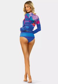 Rash guard z długim rękawem w intensywnym niebieskim kolorze z wielokolorowymi wzorami; dopasowany krój i kontrastujące, wysokie majtki kąpielowe. Gładka tekstura.