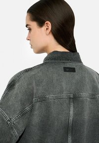 Jeansjacke in verblasstem Schwarz, mit spitzem Kragen, Rückenpasse und gesteppten Details. Inklusive einem markierten Lederetikett.