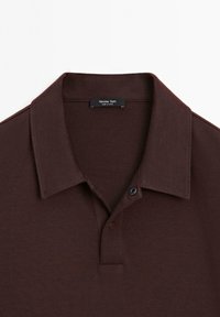 Hnědá polokošile s límečkem, s klasickým zapínáním na knoflíky a jemnou texturou. Štítek označuje "Massimo Dutti."
