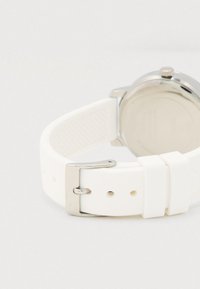 Hvid silikoneurrem med spænde i sølvmetal og strukturerede detaljer. Rundt urkasse i rustfrit stål i enden.