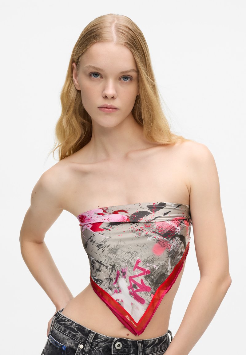 Zīda bandana triangelveida formā ar pelēku pamatu, rozā un melnā traipu rakstiem, pabeigta ar spilgti sarkanu maliņu.