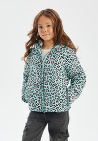 A turquoise puffer jacket with a black and pink leopard print, featuring a zip front, hood, and quilted texture. Paired with dark cargo pants.