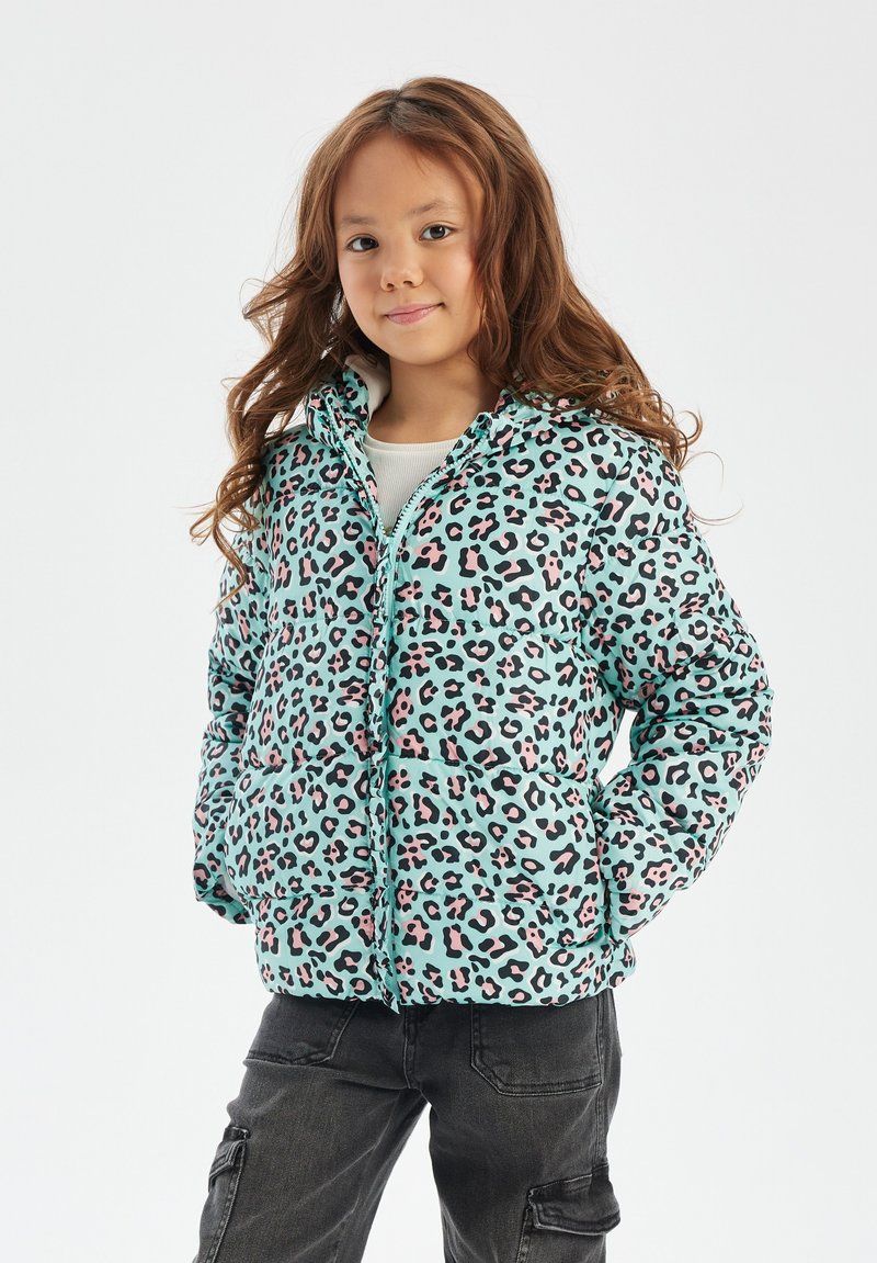 A turquoise puffer jacket with a black and pink leopard print, featuring a zip front, hood, and quilted texture. Paired with dark cargo pants.