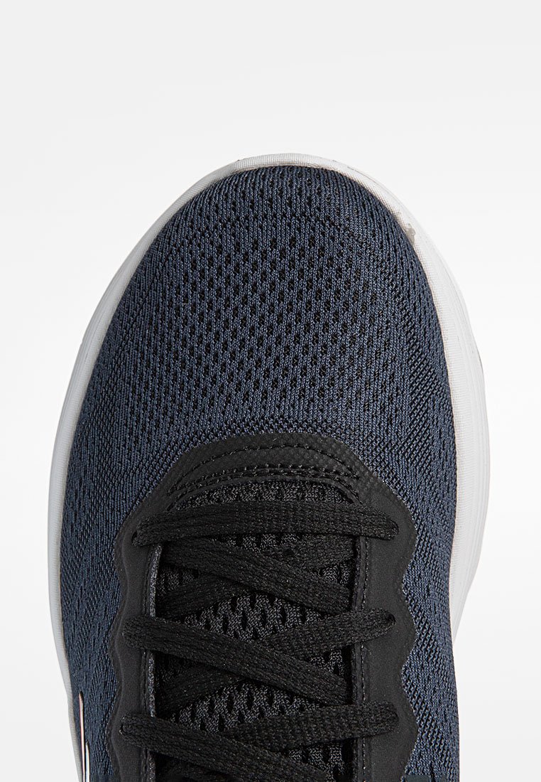 Scarpe atletiche a rete blu navy con chiusura in pizzo nero, parte superiore testurizzata e suola in gomma bianca. Presentano dettagli rinforzati nella punta.