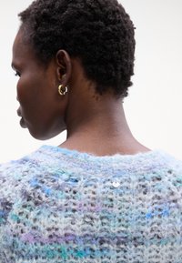 Leichter, mehrfarbiger Strickpullover mit einem lockeren, strukturierten Design in Blau- und Lilatönen; verziert mit einem kleinen silbernen Knopf.