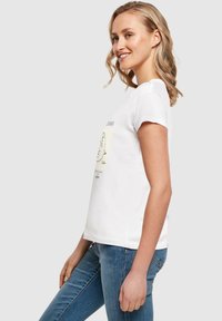 Weißes Baumwoll-T-Shirt mit kurzen Ärmeln, das mit einem grafischen Druck auf der Vorderseite versehen ist. Trägt man mit blauen Jeans. Schlichtes, lässiges Design.
