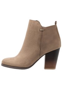 Zamszowy botek za kostkę w jasnobrązowym kolorze z wysokim, grubym obcasem. Posiada boczny zamek błyskawiczny oraz subtelne przeszycia na cholewce.