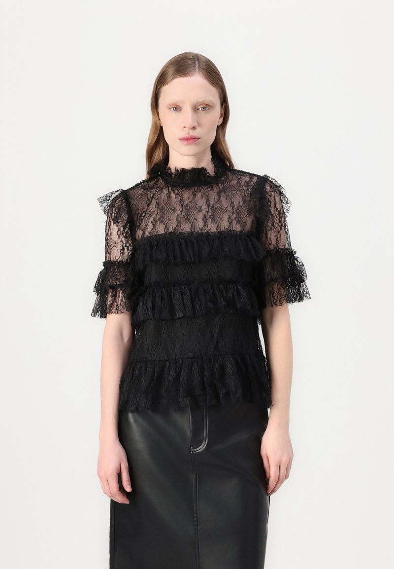Top in pizzo nero con design a volants a strati, maniche corte e scollatura alta. Il tessuto ha una texture trasparente con motivi floreali intricati.
