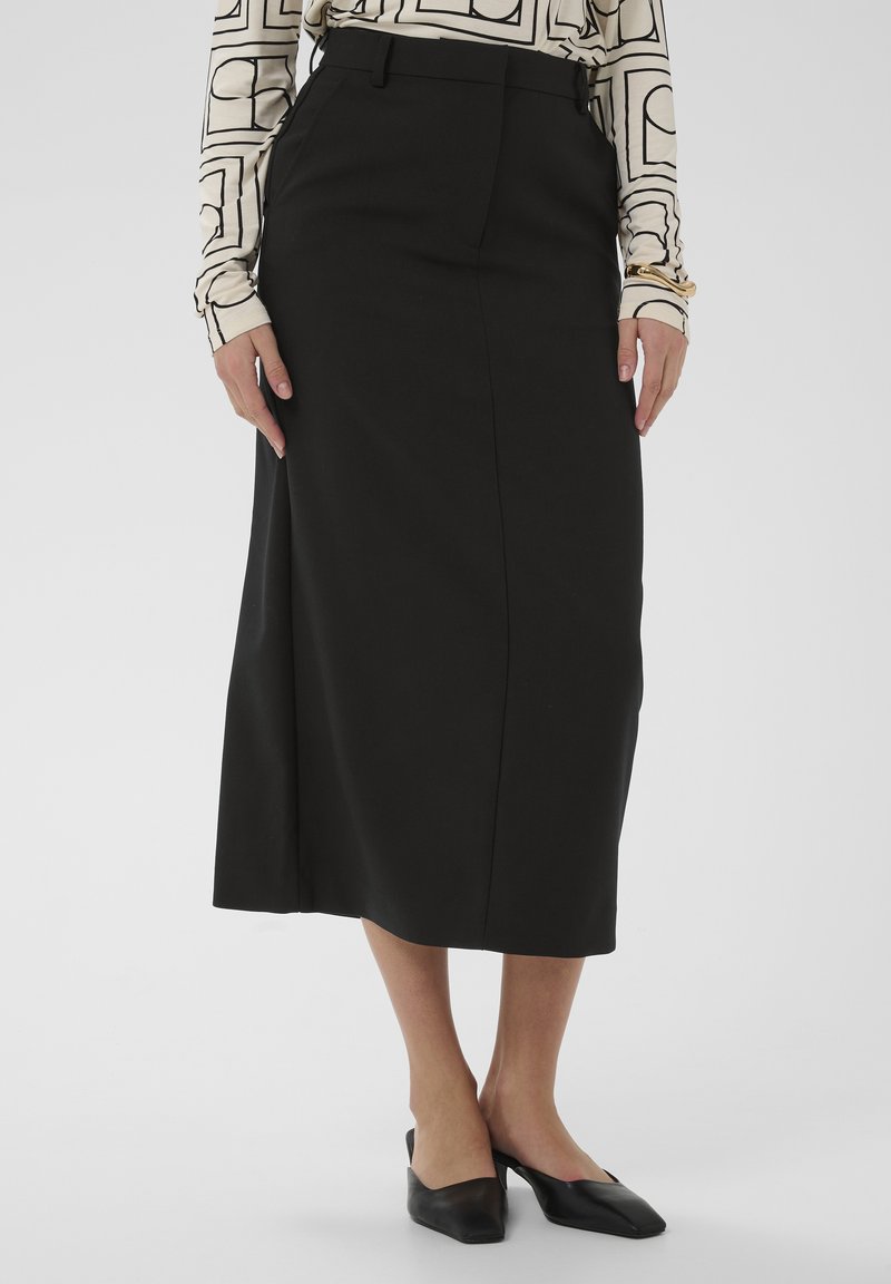 Schwarzer, hoch taillierter Midirock mit gerader Silhouette, dezenter Plisseefalten und glatter Textur, kombiniert mit schwarzen Slingback-Schuhen.