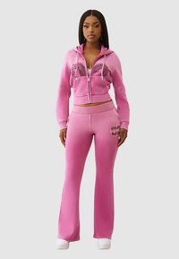 Roze hoodie en wijde broek set, met een rits aan de voorkant, getailleerde taille en grafische accenten, gemaakt van zachte, rekbare stof.