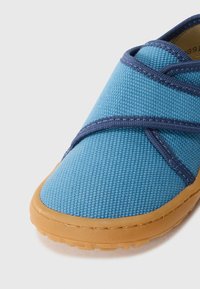 Pantof de textile albastru, slip-on, cu o suprafață texturată, având curele elastice bleumarin și o talpă flexibilă din cauciuc.