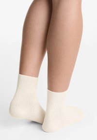 Calze alla caviglia color crema con texture a coste, caratterizzate da un morbido e elastico polsino e un design della punta senza cuciture.