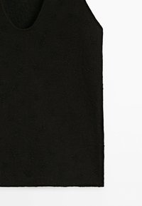 Black sleeveless top with subtle floral lace pattern and small bead embellishments scattered across the fabric.