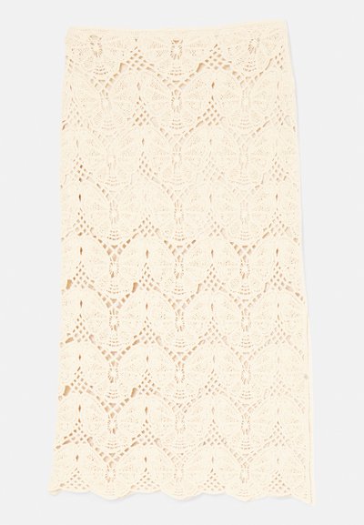 Jupe en dentelle couleur crème avec un motif de papillon, un ourlet en forme de vagues et un design perforé complexe tout au long.