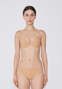 Conjunto de lencería nude que incluye un sujetador con copas moldeadas, tirantes finos ajustables y braguitas de corte bikini sin costuras, en una textura suave y mate.