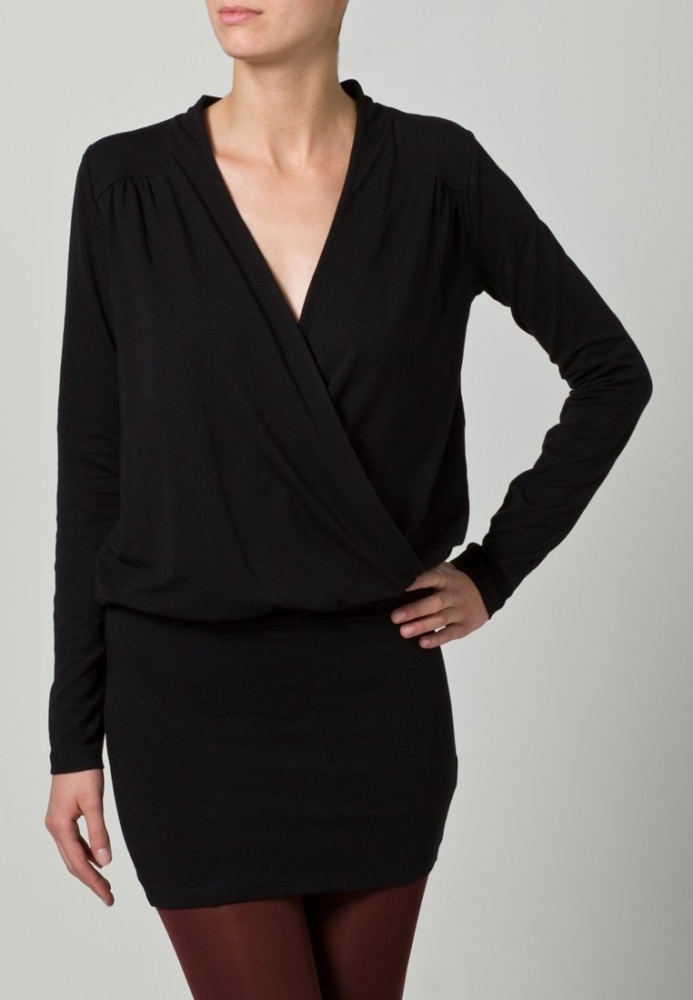 Svart långärmad omslagstopp i kombination med en figurnära minikjol. Mjuk tyg med en slät yta, med djup V-hals och skräddad axeldetalj.