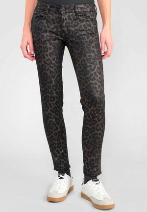 Jeans skinny con stampa leopardata nera e marrone, dotati di cinque tasche, con vita di media altezza e taglio alla caviglia, abbinati a sneakers bianche.