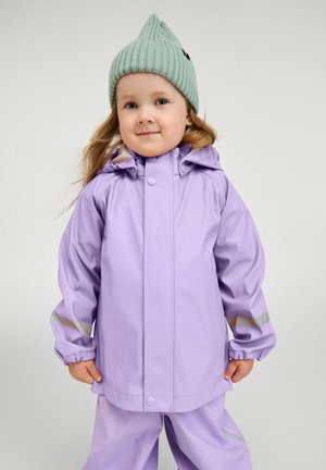 Fioletowa wodoodporna kurtka z kapturem, elastycznymi mankietami i odblaskowymi akcentami; zestawiona z dopasowanymi fioletowymi spodniami i jasnorozowym dzianinowym kapeluszem.