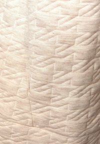 Texturovaná látka v bledě béžové barvě se vzorem diamantového cikcak. Jemný tkaný materiál s jemnými odstíny a hloubkou.