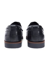 Μαύρα δερμάτινα παπούτσια με λεία επιφάνεια, διακοσμημένα με ραφές, ελάχιστες λεπτομέρειες και αντίθετη καφέ λαστιχένια σόλα.