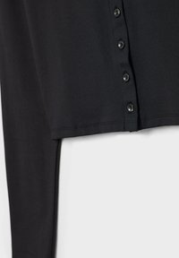 Chemise noire à manches longues avec cinq boutons noirs le long de la patte de boutonnage avant et un ourlet droit en bas.