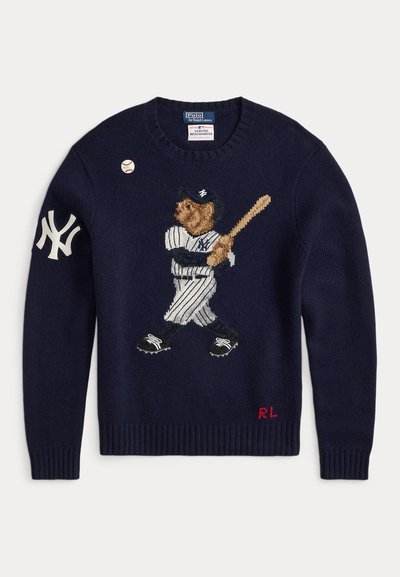 Jūras spēku zilo adījumu džemperis, kuram ir izšūts lācis beisbola tērpā, ar svītrainām biksēm un beisbola nūju, ar baltu Ņujorkas Yankees logo un sarkanu "RL" akcentu.
