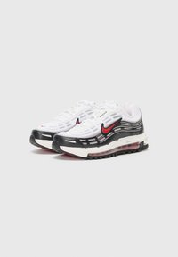Bela športna obutev z črnimi in rdečimi detajli, ki ima mrežast zgornji del, oblazinjeno podplato in izrazite elemente oblikovanja Air Max.