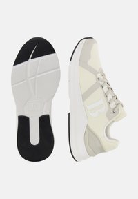 Sneaker leggera con tomaia in maglia traspirante nei toni crema e grigio. Presenta una suola texture e un logo prominente sul lato.