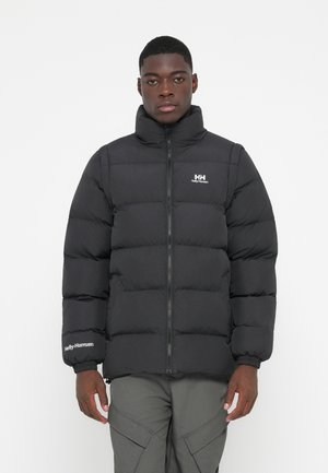 Veste matelassée noire avec col montant, fermeture éclair à l'avant et poignets élastiques. Présente le logo "Helly Hansen" sur la poitrine et la manche.