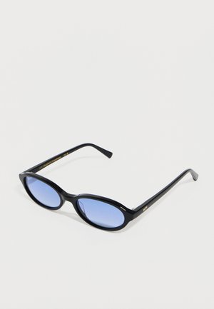 Schwarze ovale Sonnenbrille mit dünnem Rahmen und blau getönten Gläsern, liegend auf einer einfarbigen weißen Oberfläche.