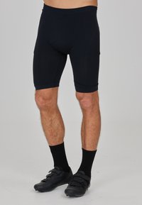Zwarte sportshorts van rekbaar materiaal, met een tailleband en een knielange snit. Draag dit met zwarte fietsschoenen en sokken.