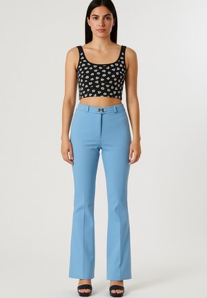 Top corto nero con motivi bianchi, abbinato a pantaloni a palazzo blu con un gancio metallico in vita. Tessuto dalla consistenza liscia.