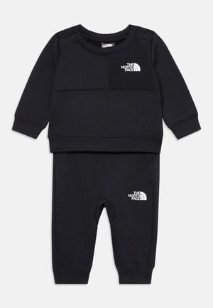Black two-piece outfit made of soft fabric, featuring a long-sleeve top with a small white logo on the chest and matching pants with logo accents.