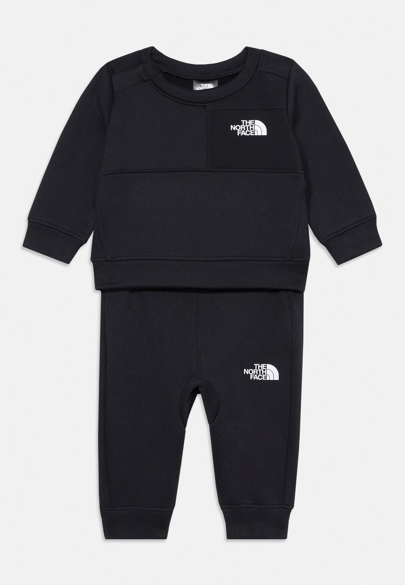 Ensemble noir en deux pièces en tissu doux, comprenant un haut à manches longues avec un petit logo blanc sur la poitrine et un pantalon assorti avec des accents de logo.