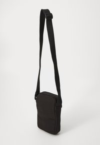 Borsa a tracolla nera in tessuto, con forma rettangolare, tracolla regolabile e chiusura superiore con zip. Texture liscia.