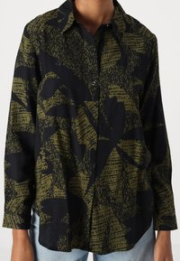 Camicia a bottone nera con un motivo astratto di foglie verde oliva. Maniche lunghe e colletto classico, realizzata in tessuto morbido.