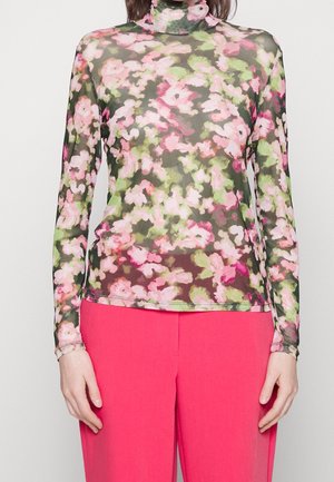 Florales, transparentes Langarm-Poloshirt mit pinkem, grünem und weißem Muster, kombiniert mit leuchtend pinken, hoch taillierten Hosen.