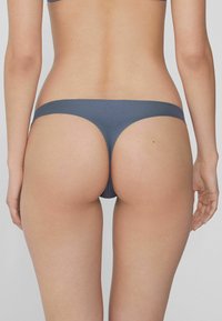 Dunkelgrauer String aus glattem Stoff, der ein minimalistisches Design mit einem schmalen Bund und moderater Abdeckung aufweist.