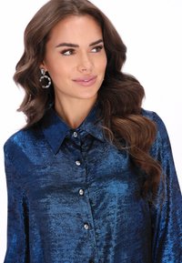 Tengerészkék szatén gombos ing hegyes gallérral, fényes gombokkal és sima, csillogó felülettel. Mintás anyaggal díszítve.