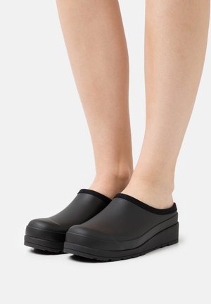 Black rubber clogs with a wedge sole, rounded toe, and a black elastic trim along the opening. Textured sole for grip.