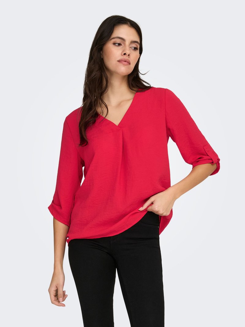 Rode blouse met V-hals gemaakt van lichtgewicht stof, met driekwart mouwen met opgerolde manchetten en een losse pasvorm, gecombineerd met een zwarte broek.