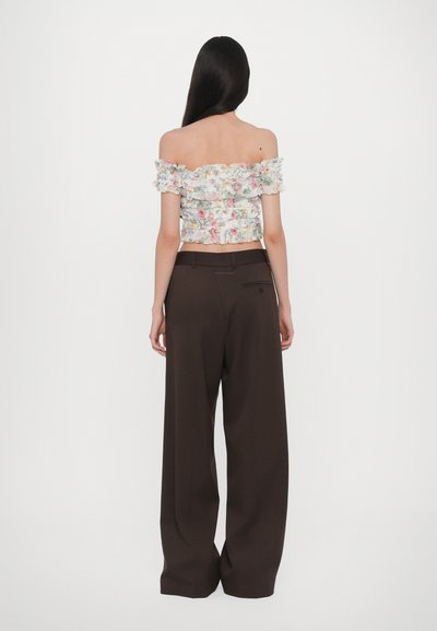 Mitmevärviline lilleline õlavabalt crop top koos frillide detailidega, millele on sobitatud kõrge vöökohaga pruunid laiad püksid.