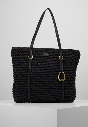 Zwarte geweven totebag met dubbele zwarte leren handvatten en gouden hardware, getoond op een witte ondergrond tegen een lichtgrijze achtergrond.