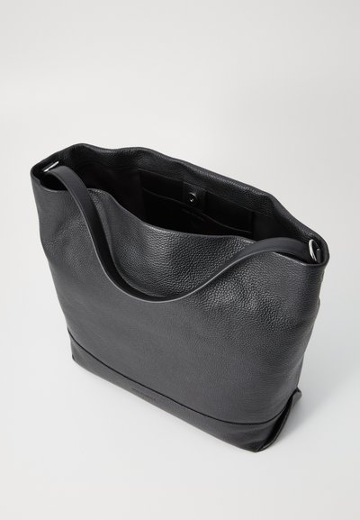 Black leather tote bag with a textured finish, open top, and a single shoulder strap. Features a magnetic snap closure and minimal design.