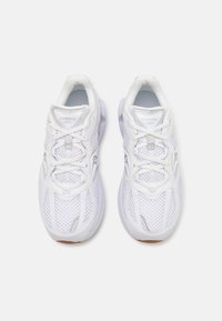 Scarpe da ginnastica bianche con tomaia in rete, chiusura con lacci, suole in gomma e pannelli testurizzati. Presentano dettagli riflettenti e logo.