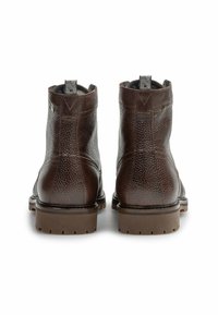 Bottines en cuir marron avec une texture granuleuse, bout rond, coutures décoratives et une semelle en caoutchouc robuste. Langettes pour un enfilage facile.
