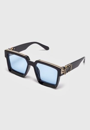 Mustat neliönmuotoiset aurinkolasit vaaleansinisillä linsseillä ja kullanvärisillä koristeilla kehyksissä ja varsissa, esillä yksinkertaisella taustalla.