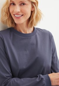Langärmeliges, rundhalsiges Oberteil aus weichem, marineblauem Baumwollstoff mit glatter Textur. Verfügt über gerippte Bündchen und eine lässige Passform.